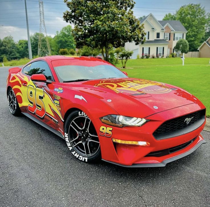 a red sports car with flames painted on the hood is parked in front of a house