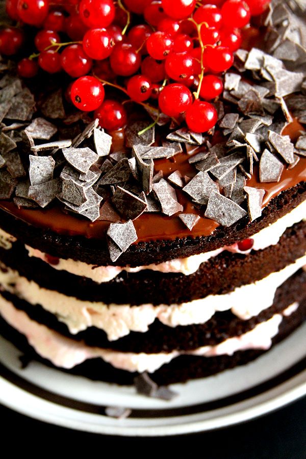 a chocolate cake topped with cherries on top of a white plate