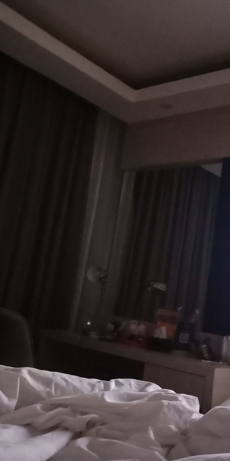 an unmade bed in a hotel room with a television on the wall behind it