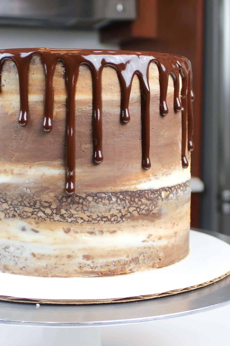 a cake with chocolate drizzle and frosting on top sitting on a table