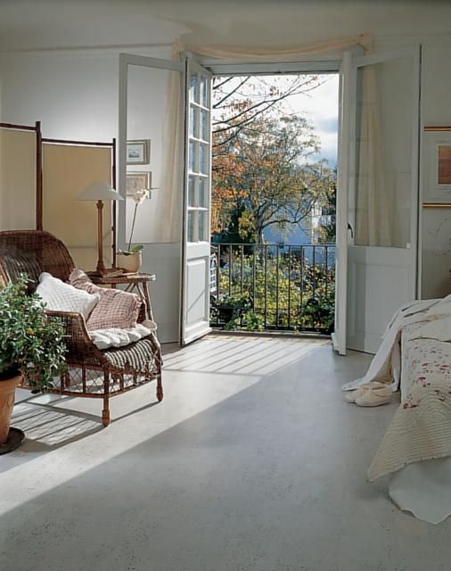 a bedroom with an open door leading to a balcony and patio area that has potted plants on either side of the bed