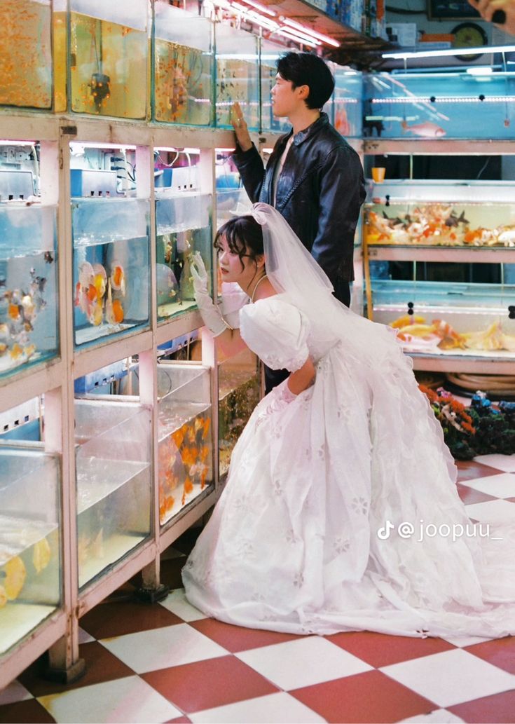 a bride and groom looking at fish in a store