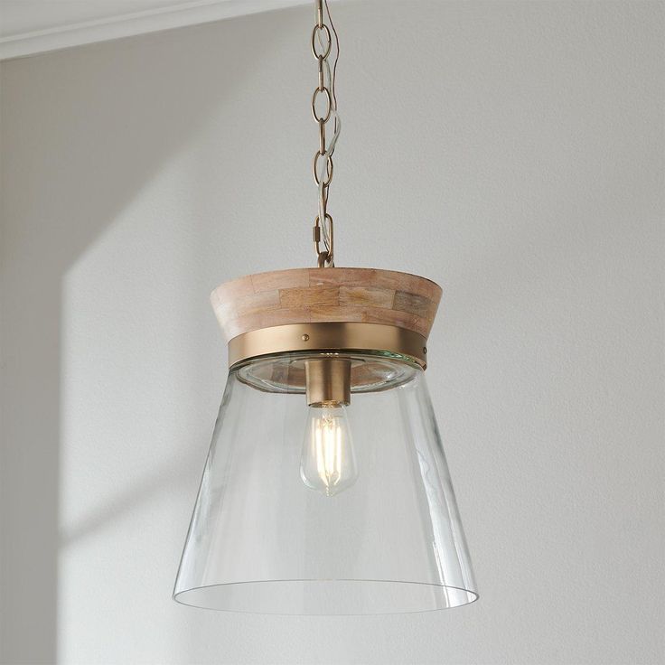 a wooden and glass light fixture hanging from a ceiling in a room with white walls