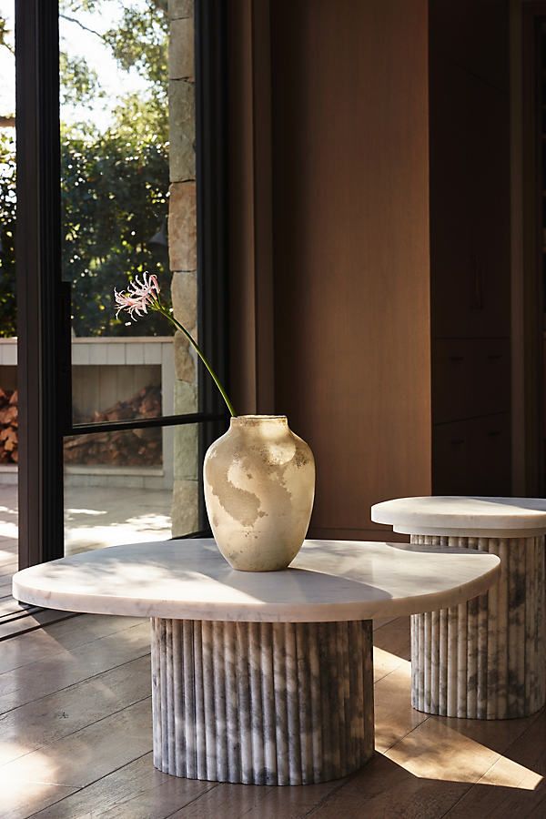 a white vase sitting on top of a table next to two tables with flowers in it