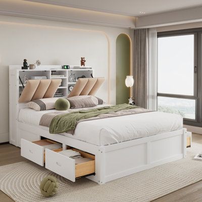 a white bed sitting in a bedroom next to an open book shelf on top of a wooden floor