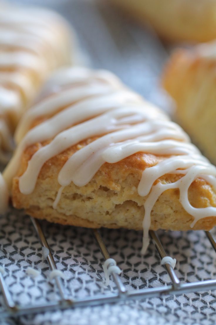 there are some scones with icing on the cooling rack in front of them