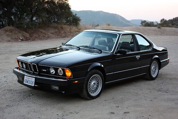 a black bmw is parked in the dirt