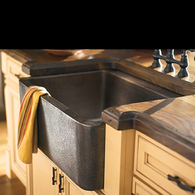 a kitchen sink sitting under a window next to a wooden counter top with a towel hanging on it