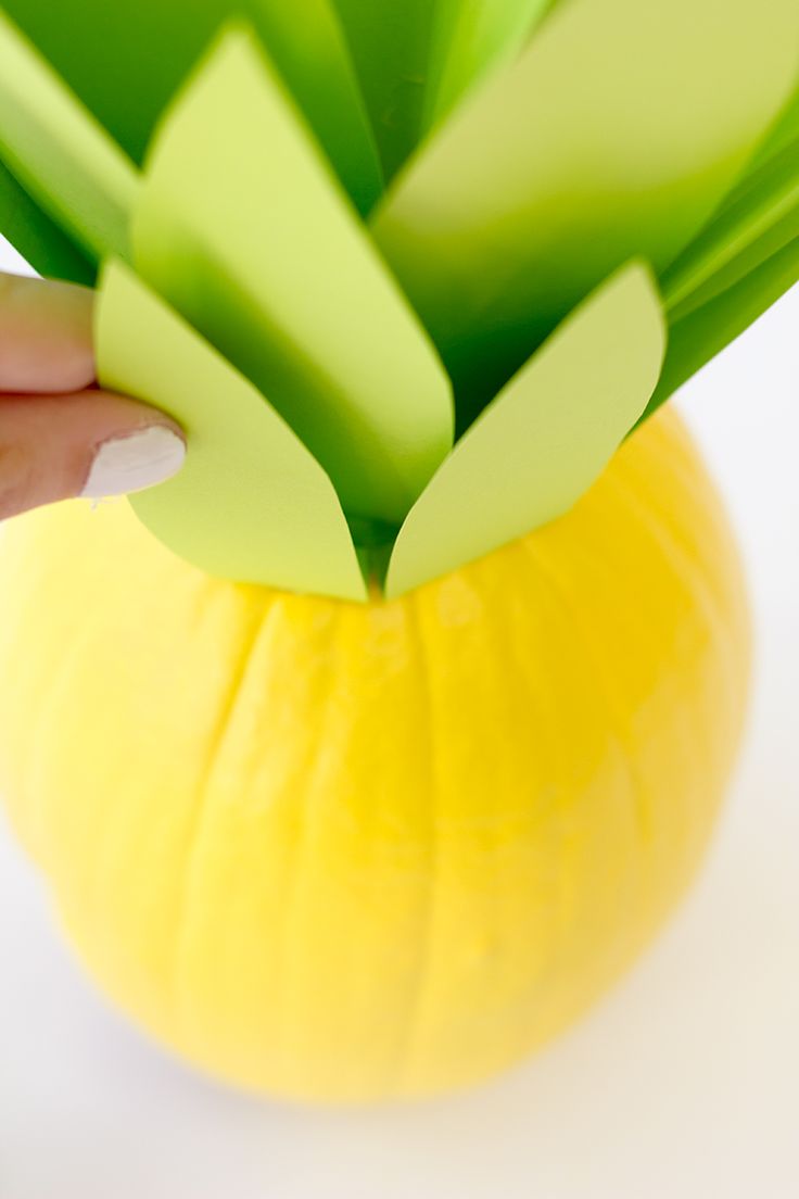 a person is holding up a paper cut out of a flower in a yellow vase