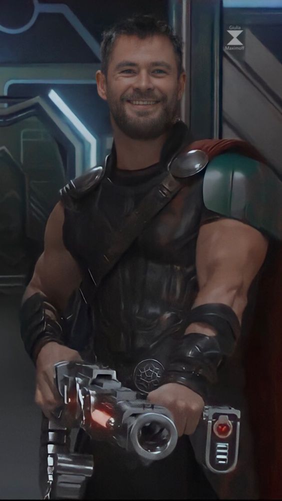 a man dressed as thor holding a camera in his right hand and smiling at the camera