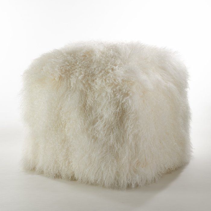 a fluffy white ottoman sitting on top of a table