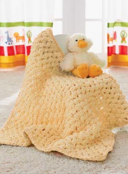 a crocheted blanket on the floor with a stuffed duck sitting on top of it