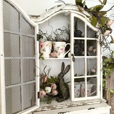 an old china cabinet is decorated with flowers and teacups on it's shelves