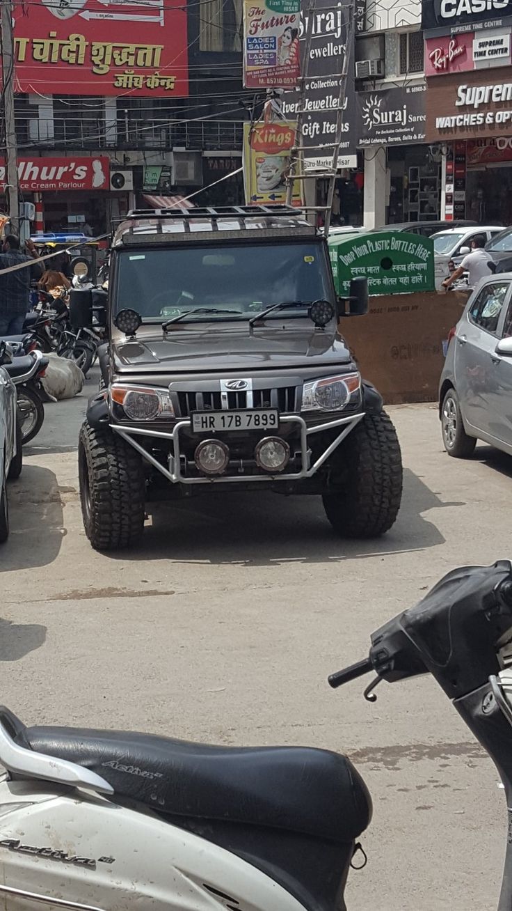 several vehicles are parked on the street in front of shops and businesses, including motorcycles