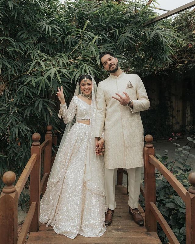 a man and woman standing on top of a wooden bridge holding hands in the air