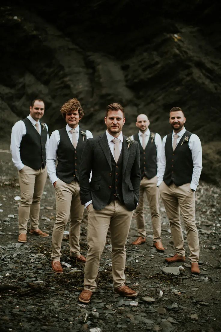 a group of men standing next to each other on top of a rocky field with trees in the background