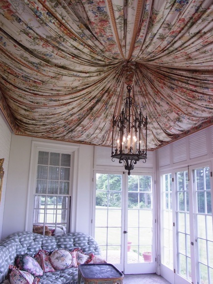 a living room with a couch, chandelier and large window covered in curtains