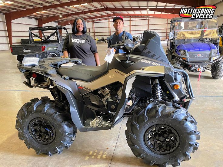 two people standing next to an atv in a garage