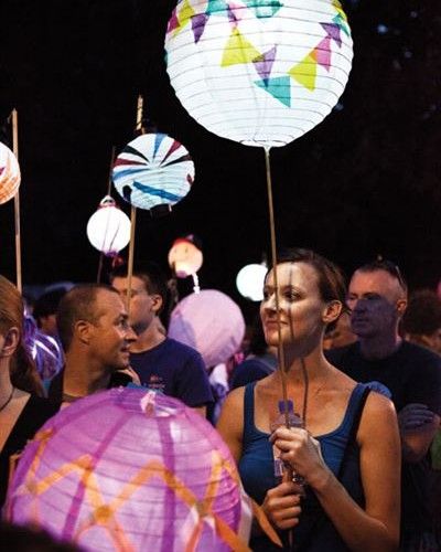 a group of people standing next to each other with paper lanterns in the shape of stars