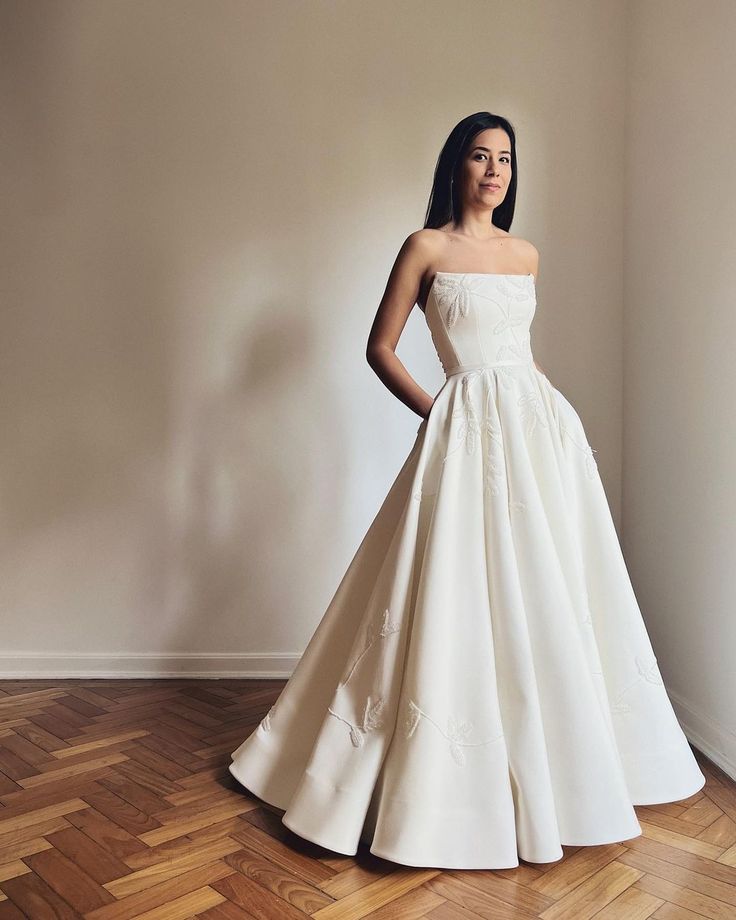 a woman in a white dress standing on a wooden floor with her hands on her hips