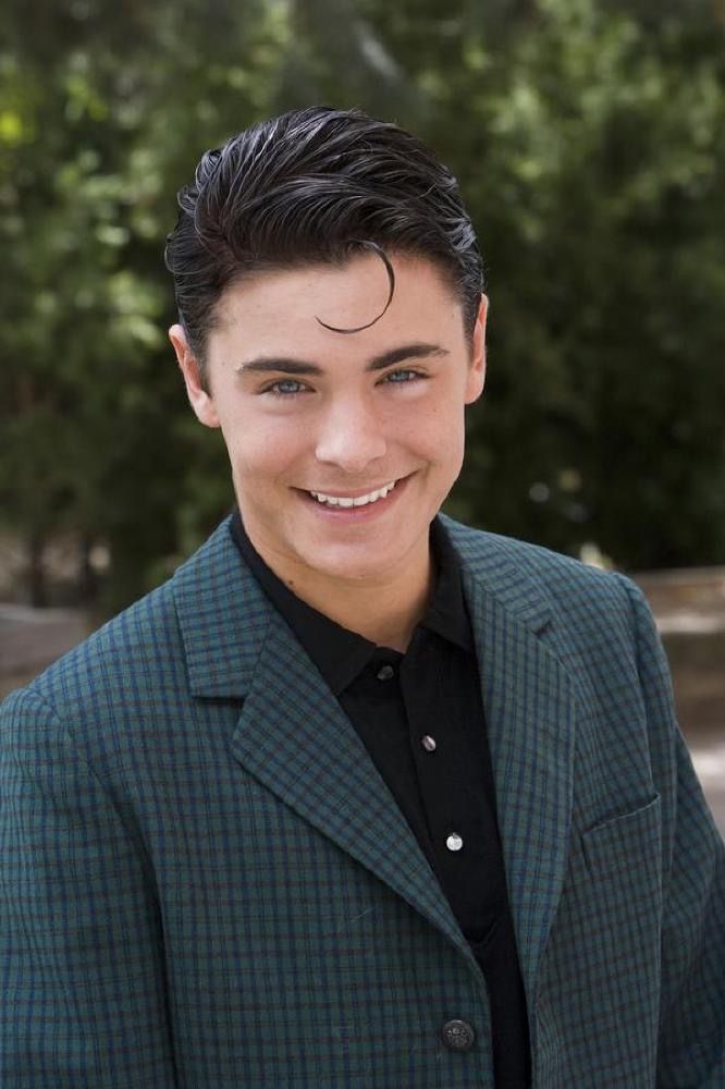 a young man in a suit smiling at the camera