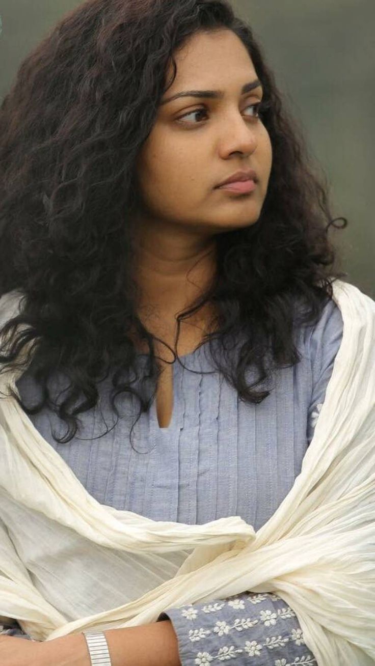 a close up of a person with long hair wearing a blue shirt and white shawl