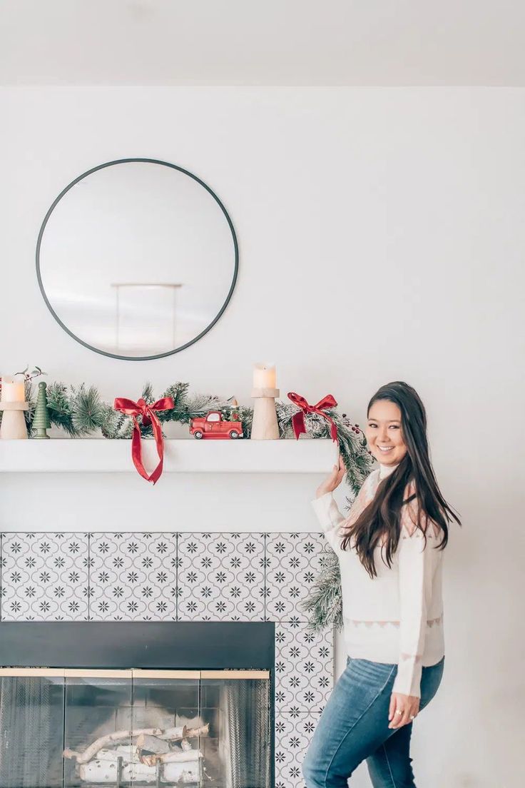 a woman standing in front of a fireplace with christmas decorations on the mantel and mantle