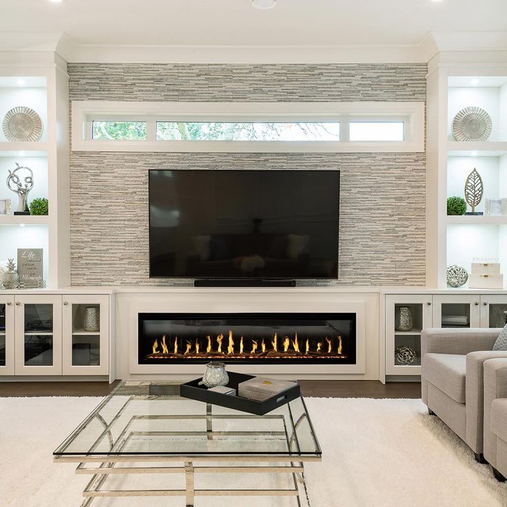 a living room with a fireplace, couches and a flat screen tv on the wall