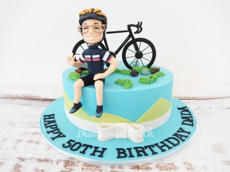 a birthday cake with a man sitting on top of it, holding a bike and wearing a bow tie