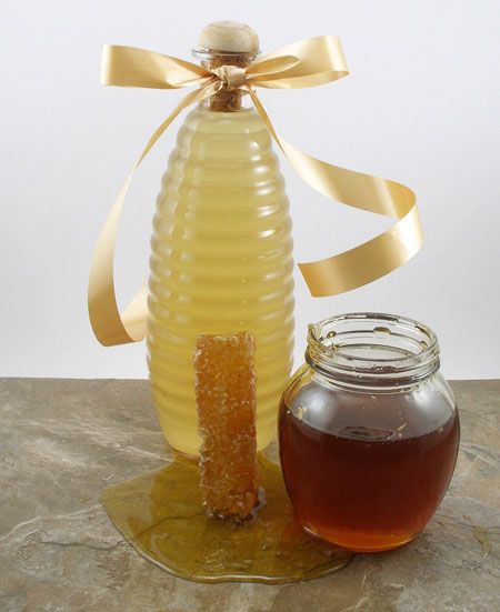 a jar of honey next to a bottle of honey with a ribbon on the top