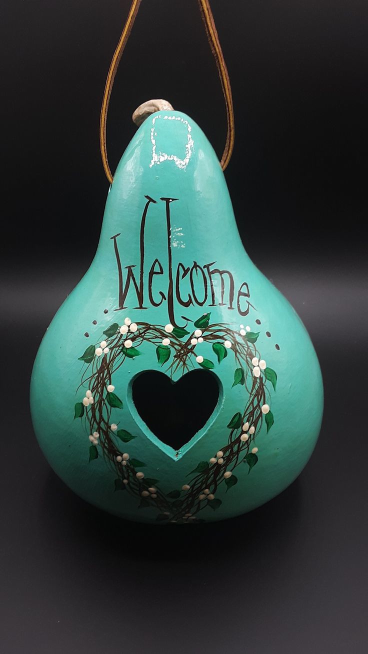 a green vase with a welcome sign painted on the side and a heart in the middle