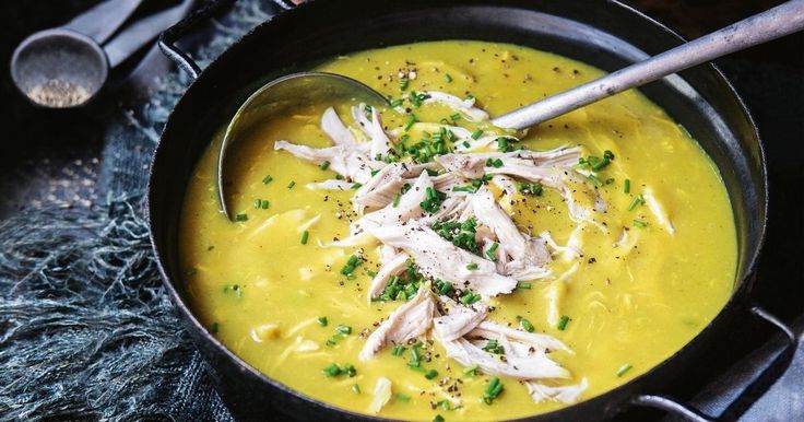 a black bowl filled with soup and two spoons