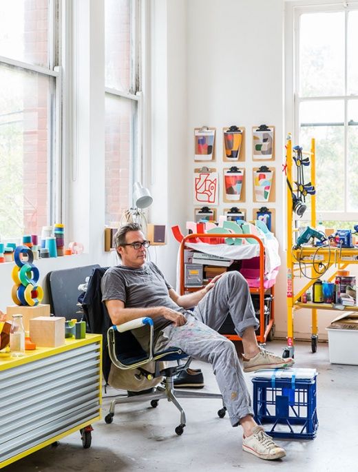 a man sitting in a chair next to a desk with lots of toys on it