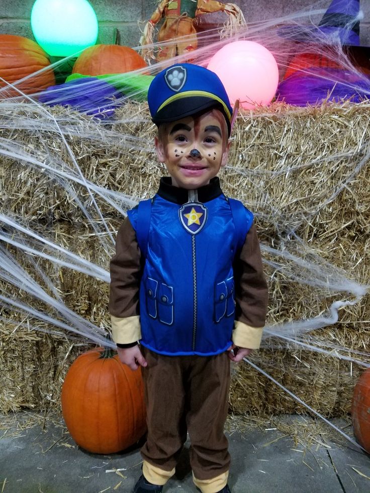 a young boy dressed as a police officer stands in front of hay bales and pumpkins