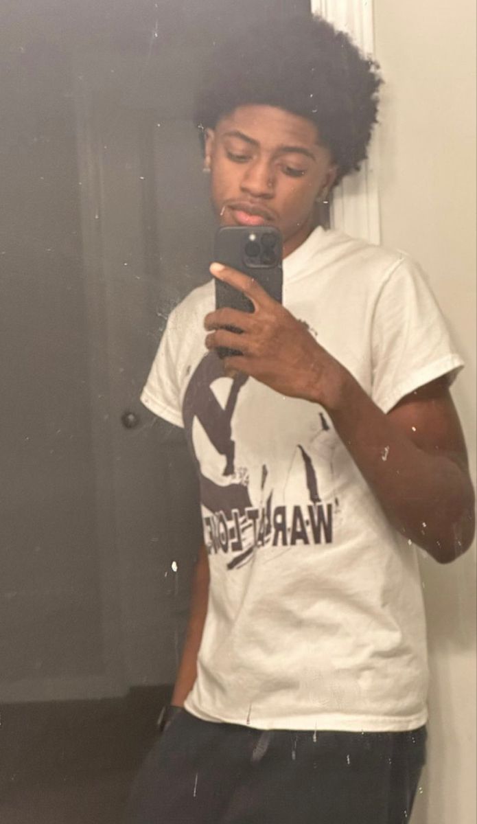 a young man taking a selfie in front of a mirror with his cell phone