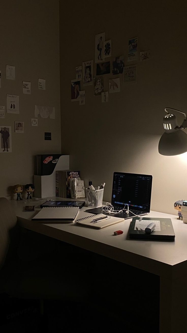 a desk with a laptop computer sitting on top of it next to a lamp and other items