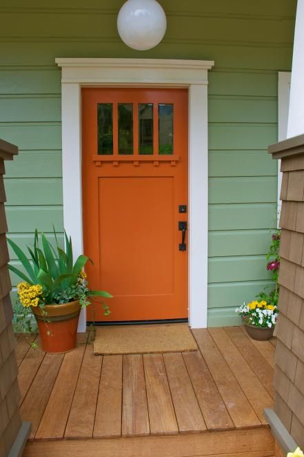 an orange front door on a green house