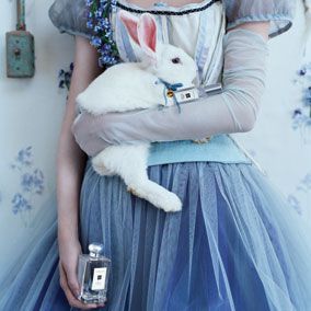 a woman holding a white rabbit in her arms and wearing a blue tutu skirt