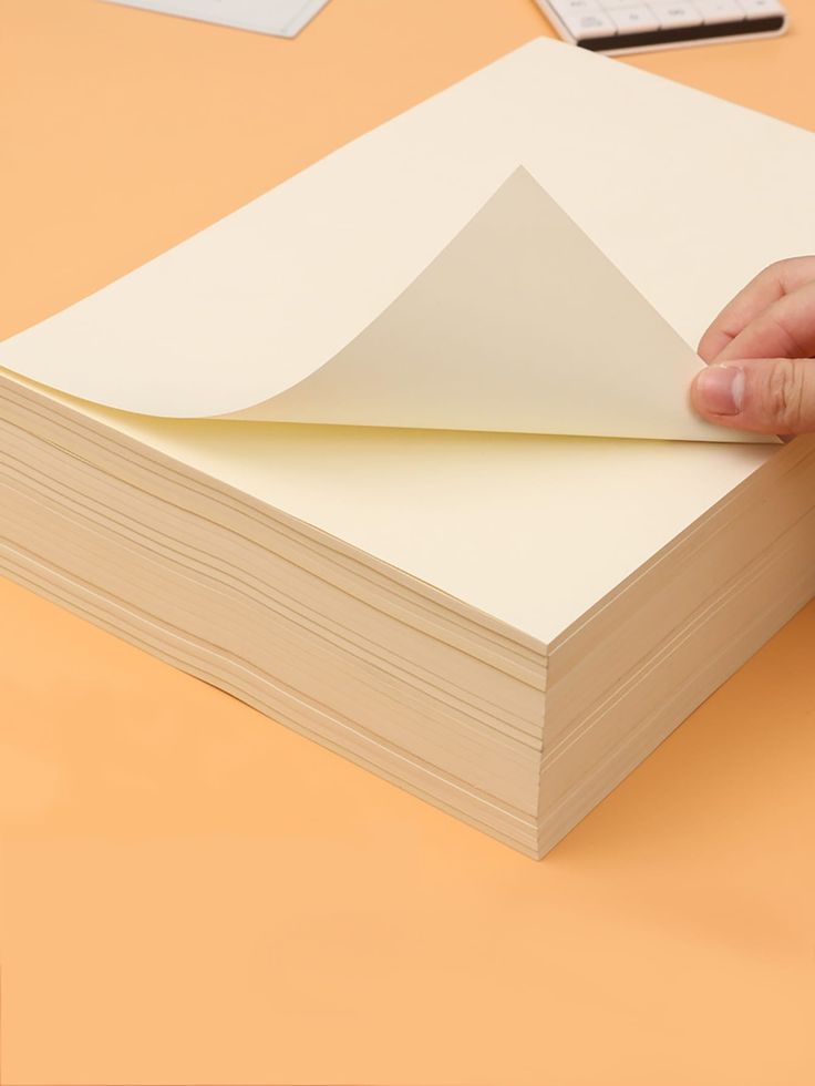 a hand is holding a piece of paper on top of a book that has been folded