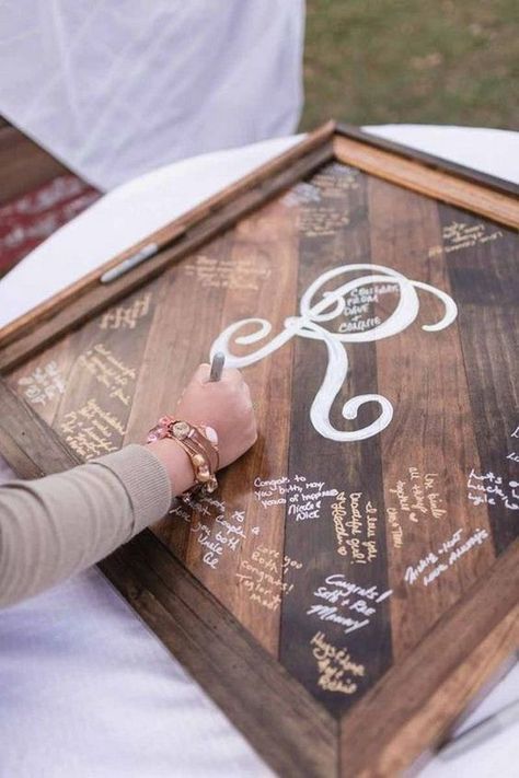 a person is writing on a wooden sign