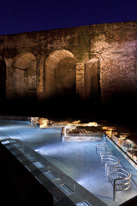 an outdoor swimming pool at night with chairs