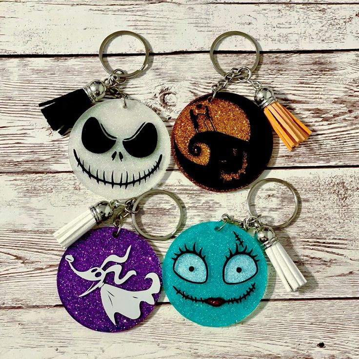 three keychains with different designs on them sitting on a wooden surface in front of a white background