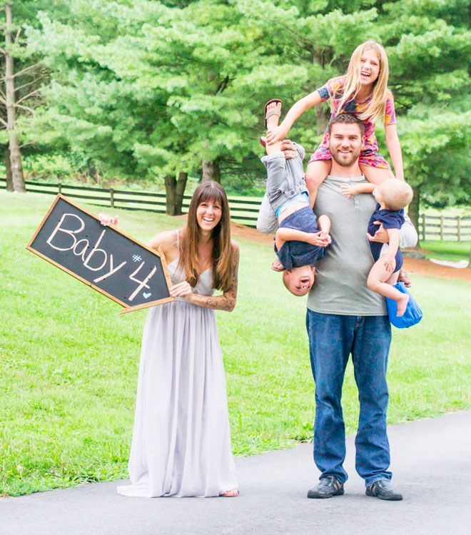 a family poses for a photo while holding a sign that says baby 4