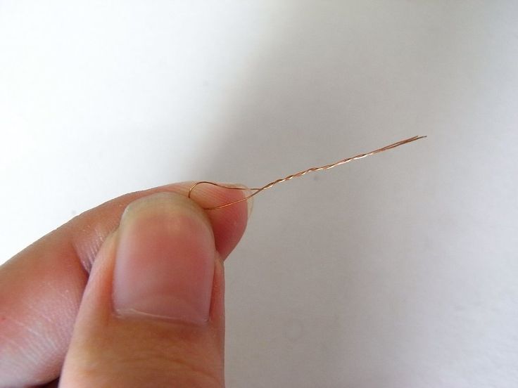 a person holding a tiny piece of wire in their left hand, with the end of it