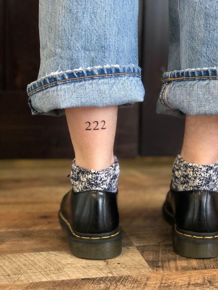 the legs and ankles of a person wearing black clogs with numbers on them