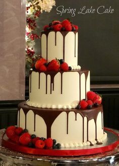 a three tiered cake with chocolate and strawberries on top