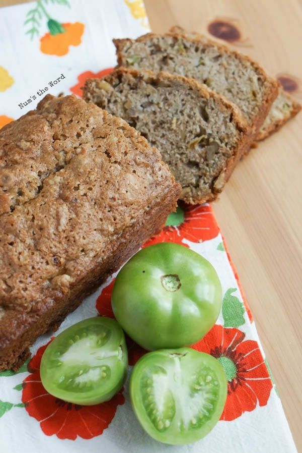 two slices of bread and three green tomatoes on a floral napkin with a flower design