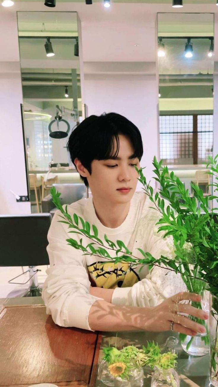 a man sitting at a table with plants in front of him