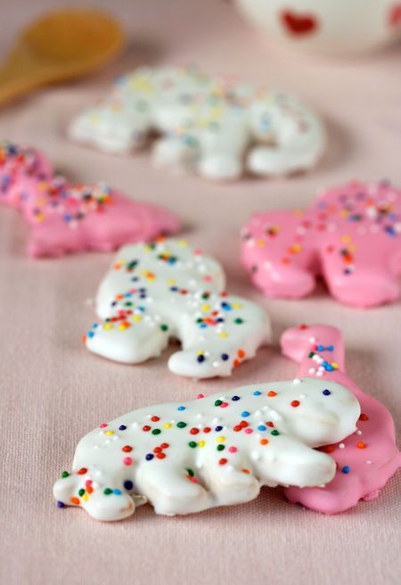 some pink and white frosted cookies with sprinkles on them are sitting on a table