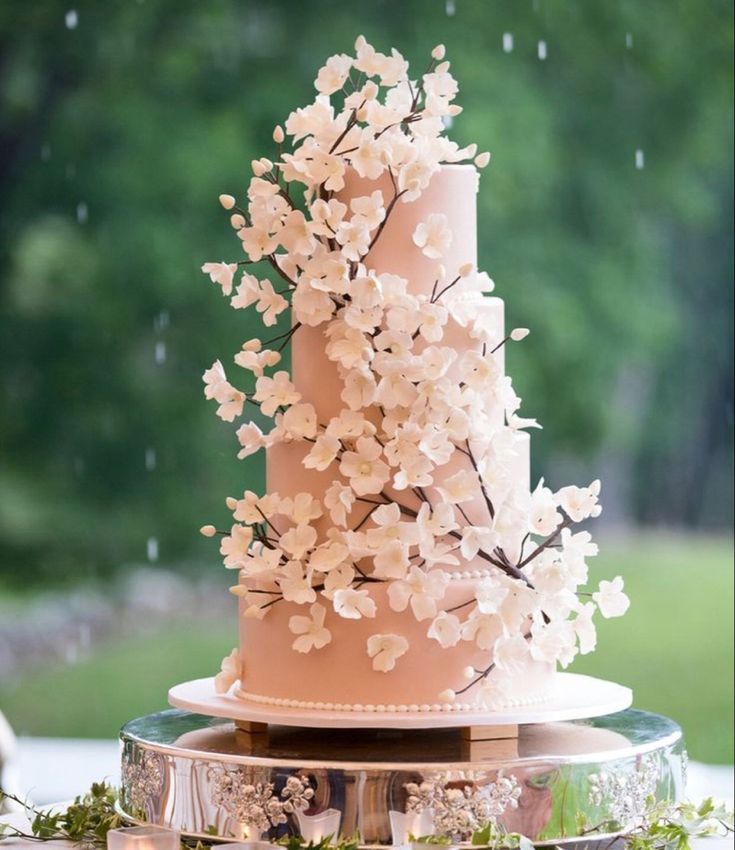 a pink wedding cake with white flowers on top